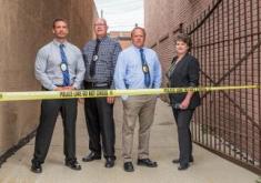 Investigations team standing behind crime scene tape